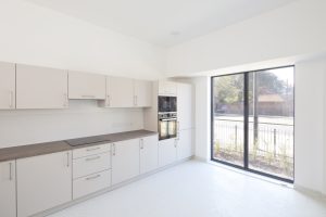 Image shows open plan fitted kitchen with French doors